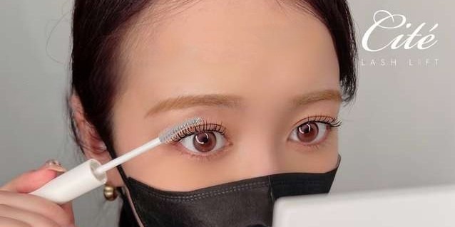 自分でコーティング剤をまつ毛に塗っている様子の目元のアップ